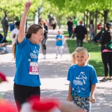 Girls on the Run participant is cheered on by coach at 5K
