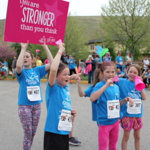 Girls hold up sign cheering on runners at 5K