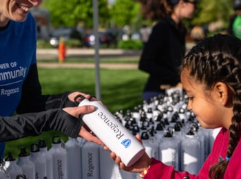 Girl receives water bottle from sponsor